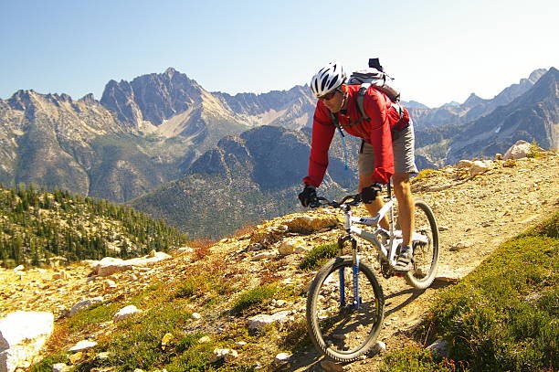 un home en vélo de montage avec un casque sur un sentier montagneux